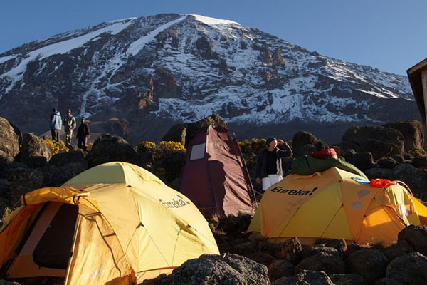 Snow-covered peak of Mount Kilimanjaro seen from the base camp with its tents