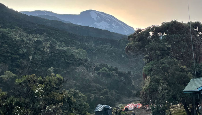 Machame Camp on Mount Kilimanjaro with views of green hills and the snow-capped mountain top